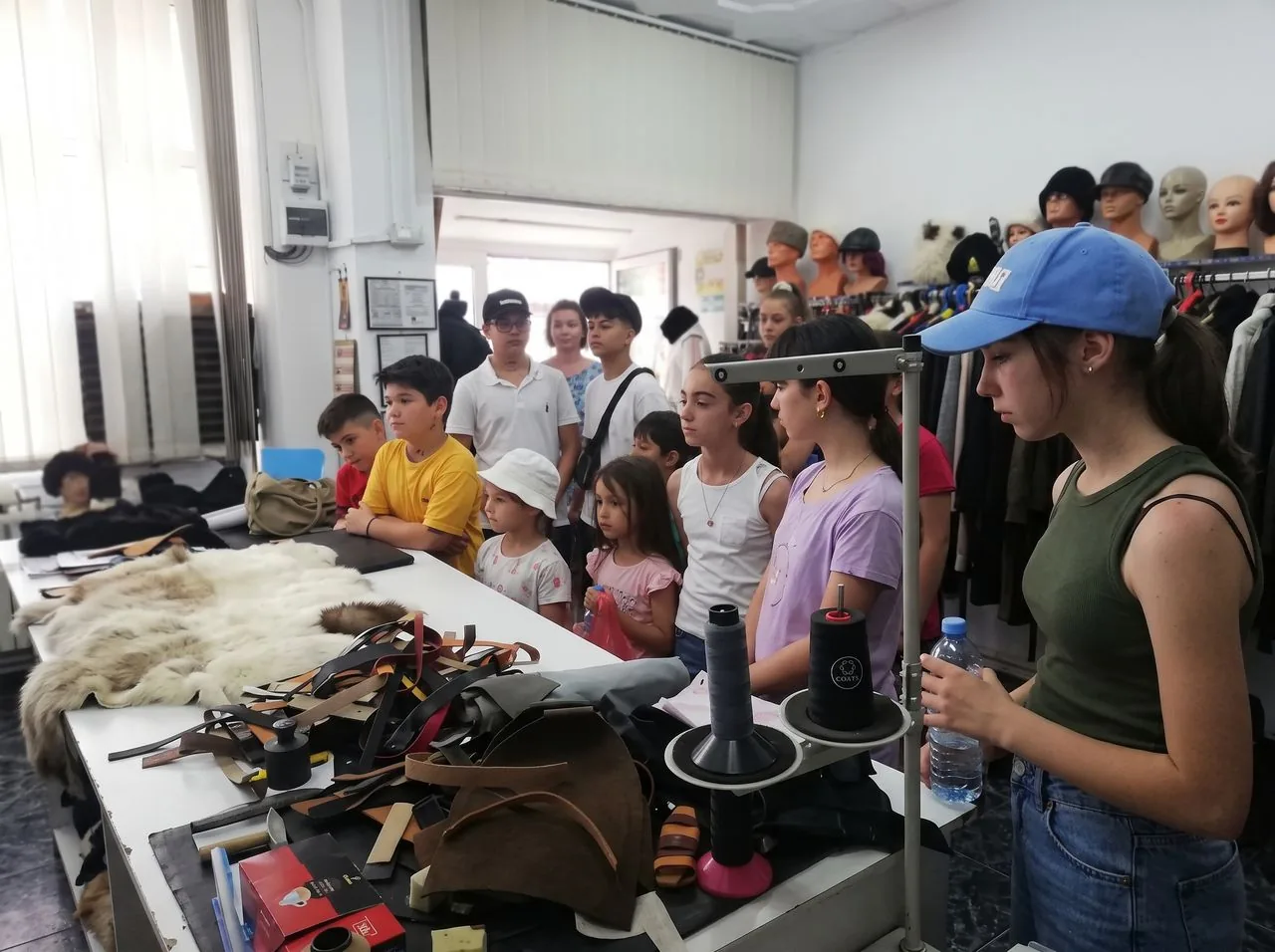 Un grup de copii adunat de-a lungul mesei de croit din atelier.