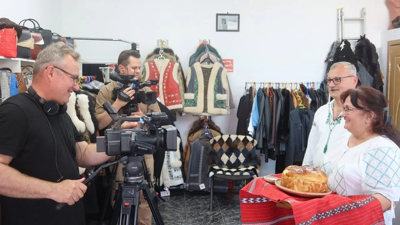 O echipă de televiziune filmează în atelier, cu camera așezată pe trepied.