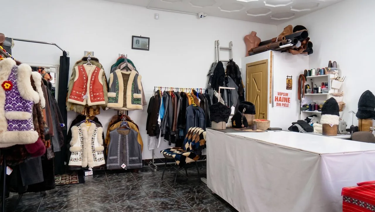 Magazinul și atelierul din Brăila, într-o singură încăpere: bundițe pe perete, cojoace pe umeraș și masa de croit alături